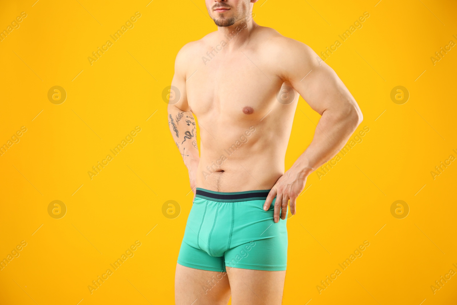 Young man in stylish turquoise underwear on orange background, closeup Photo of Young man in stylish turquoise underwear on orange background, closeup