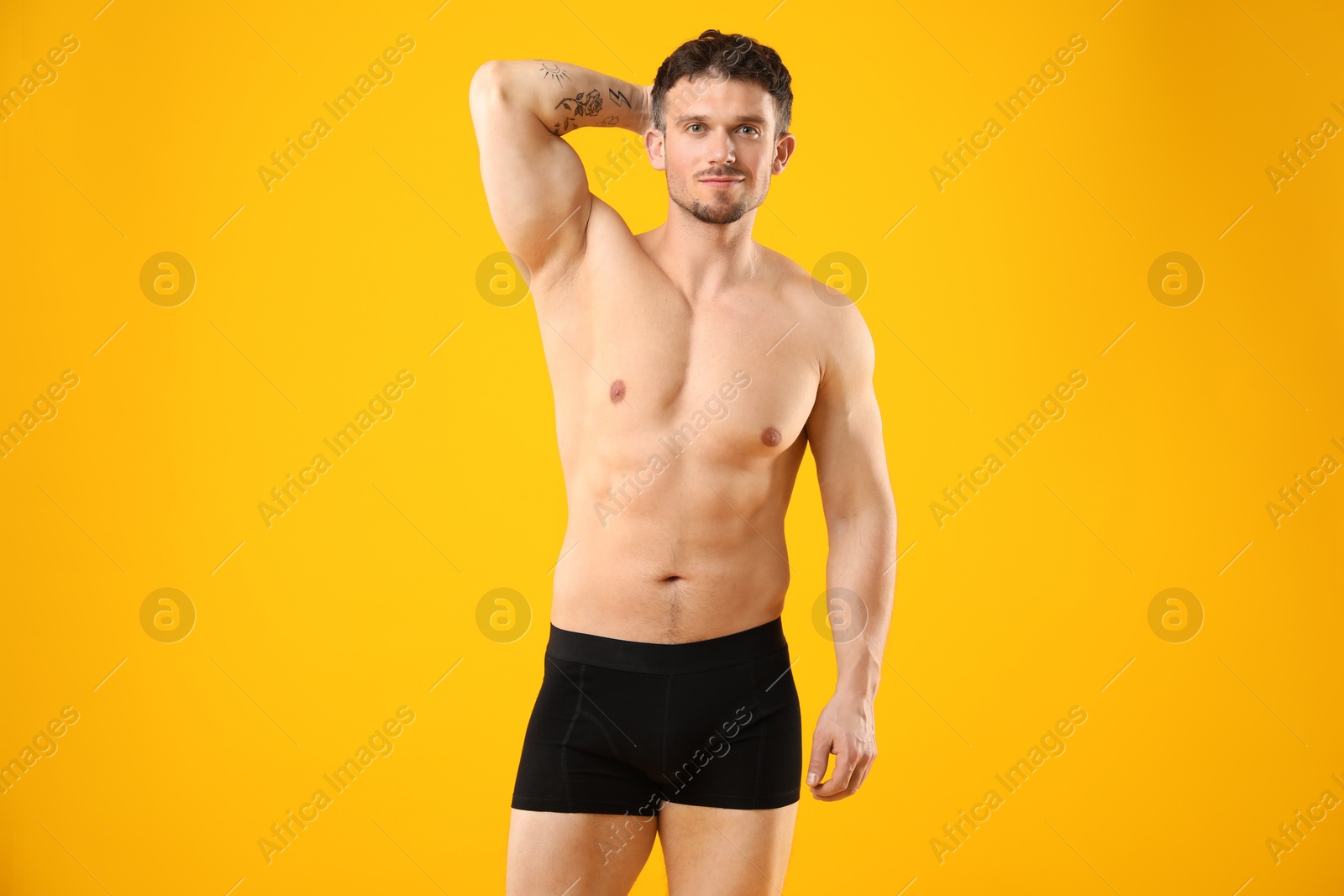 Young man in stylish black underwear on orange background Photo of Young man in stylish black underwear on orange background