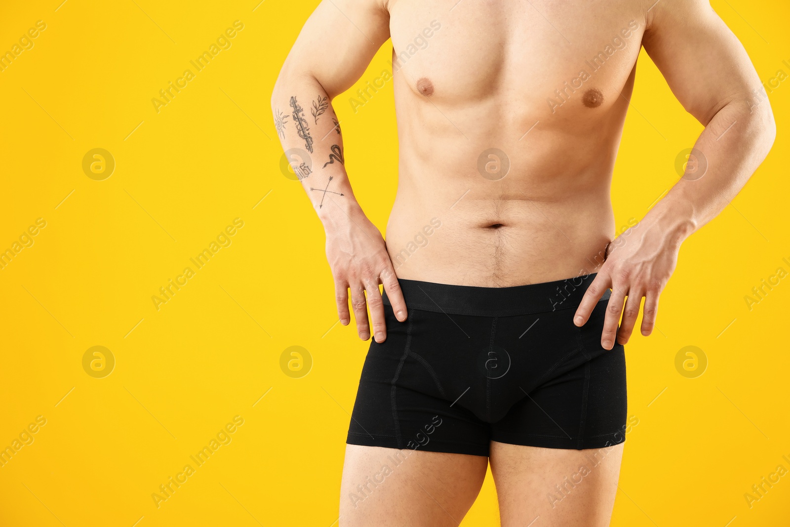 Young man in stylish black underwear on orange background, closeup. Space for text Photo of Young man in stylish black underwear on orange background, closeup. Space for text