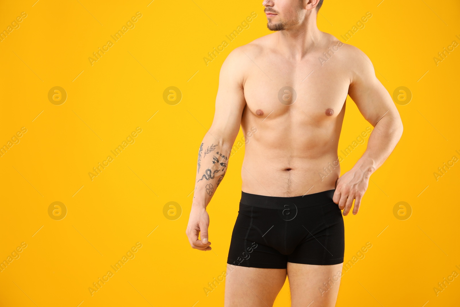 Young man in stylish black underwear on orange background, closeup. Space for text Photo of Young man in stylish black underwear on orange background, closeup. Space for text
