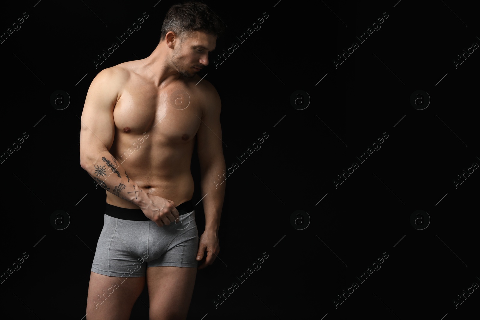 Young man in stylish light grey underwear on black background. Space for text Photo of Young man in stylish light grey underwear on black background. Space for text