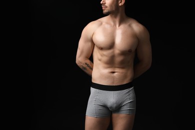 Photo of Young man in stylish light grey underwear on black background, closeup