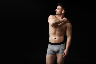 Photo of Young man in stylish light grey underwear on black background. Space for text