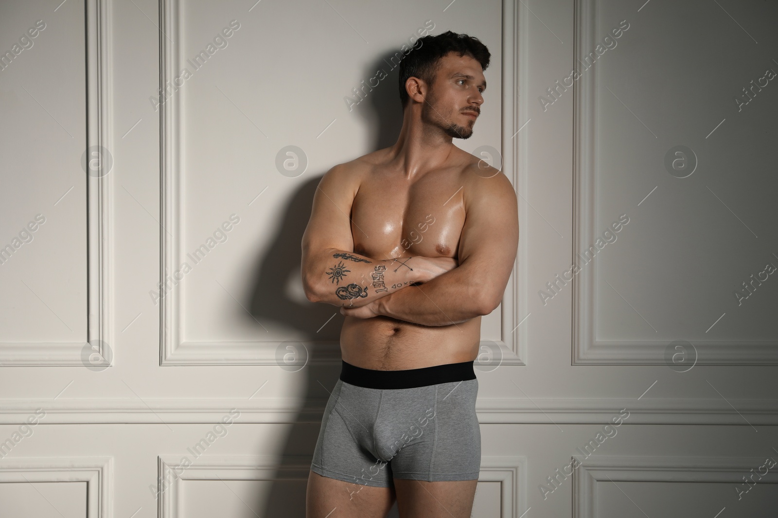 Young man in stylish light grey underwear near white wall indoors Photo of Young man in stylish light grey underwear near white wall indoors