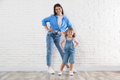 Photo of Beautiful mother and her little daughter near white brick wall