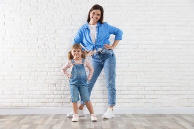 Photo of Beautiful mother and her little daughter near white brick wall