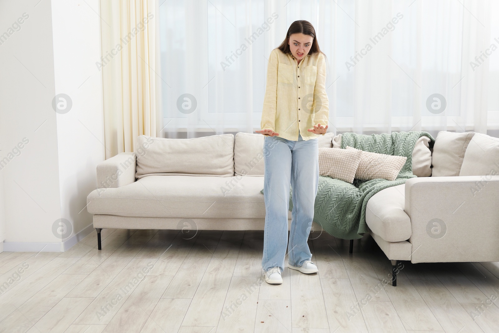 Emotional young woman looking in disgust at cockroaches on floor indoors. Pest problem Photo of Emotional young woman looking in disgust at cockroaches on floor indoors. Pest problem