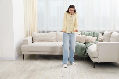 Photo of Emotional young woman looking in disgust at cockroaches on floor indoors. Pest problem