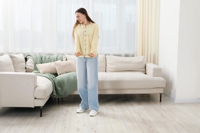 Photo of Emotional young woman looking in disgust at cockroaches on floor indoors. Pest problem