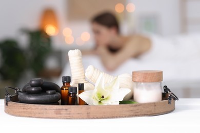 Photo of Woman relaxing in salon, focus on spa products and flower