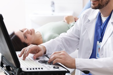 Photo of Sonographer with ultrasound machine and woman waiting for examination in clinic, selective focus