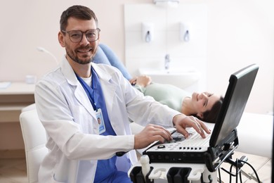 Photo of Sonographer with ultrasound machine and woman waiting for examination in clinic, selective focus