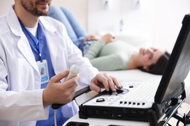 Photo of Sonographer with ultrasound transducer and woman waiting for examination in clinic, selective focus