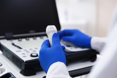Photo of Sonographer with transducer and ultrasound machine in clinic, closeup