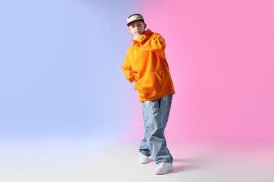 Photo of Boy in stylish clothes dancing on color background, space for text
