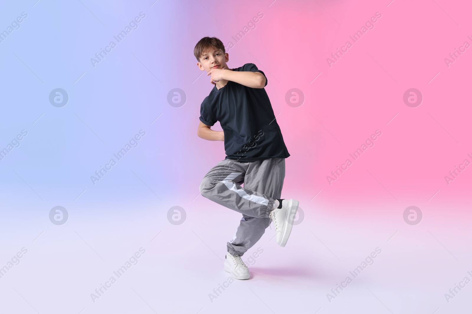 Boy in stylish clothes dancing on color background Photo of Boy in stylish clothes dancing on color background