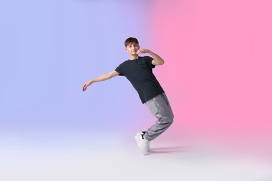 Photo of Boy in stylish clothes dancing on color background