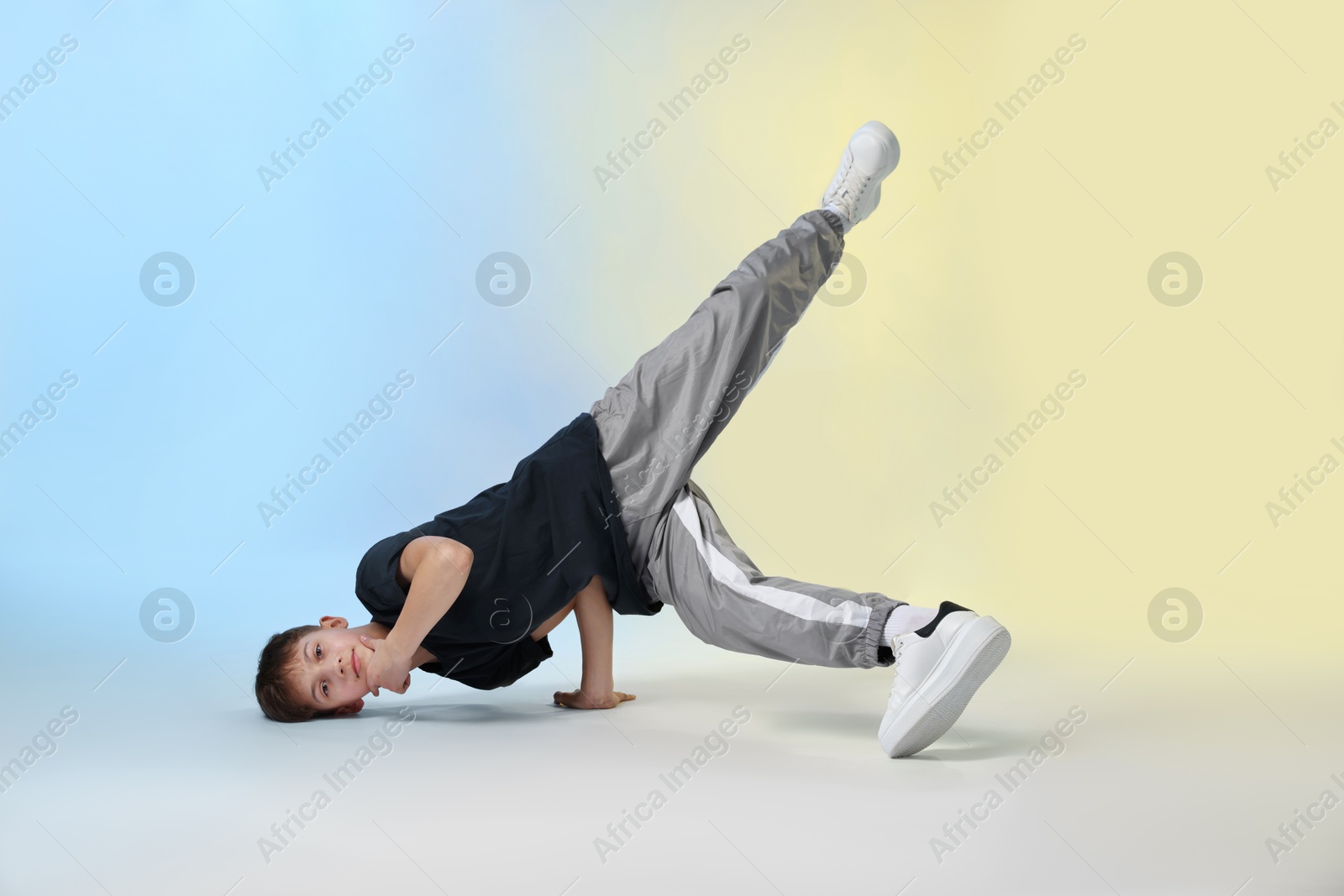 Boy in stylish clothes dancing on color background Photo of Boy in stylish clothes dancing on color background