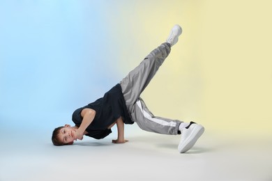Photo of Boy in stylish clothes dancing on color background