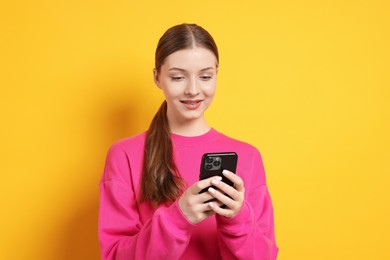 Photo of Teenage girl with smartphone on yellow background