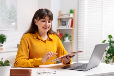 Photo of Woman using modern tablet at desk indoors. Space for text