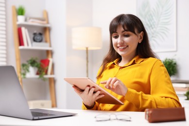 Photo of Woman using modern tablet at desk indoors. Space for text