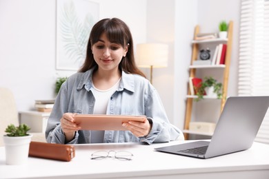 Photo of Woman using modern tablet at desk indoors