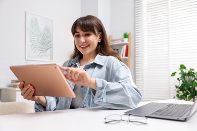 Photo of Woman using modern tablet at desk indoors