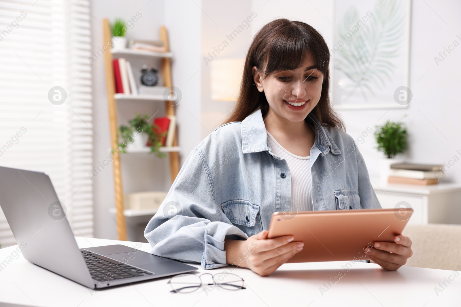 Woman using modern tablet at desk indoors Photo of Woman using modern tablet at desk indoors