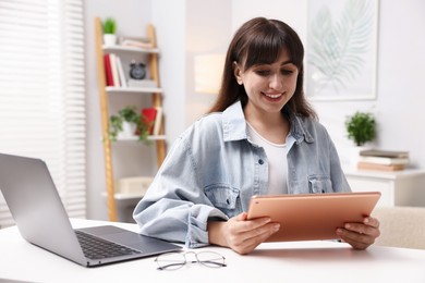 Photo of Woman using modern tablet at desk indoors