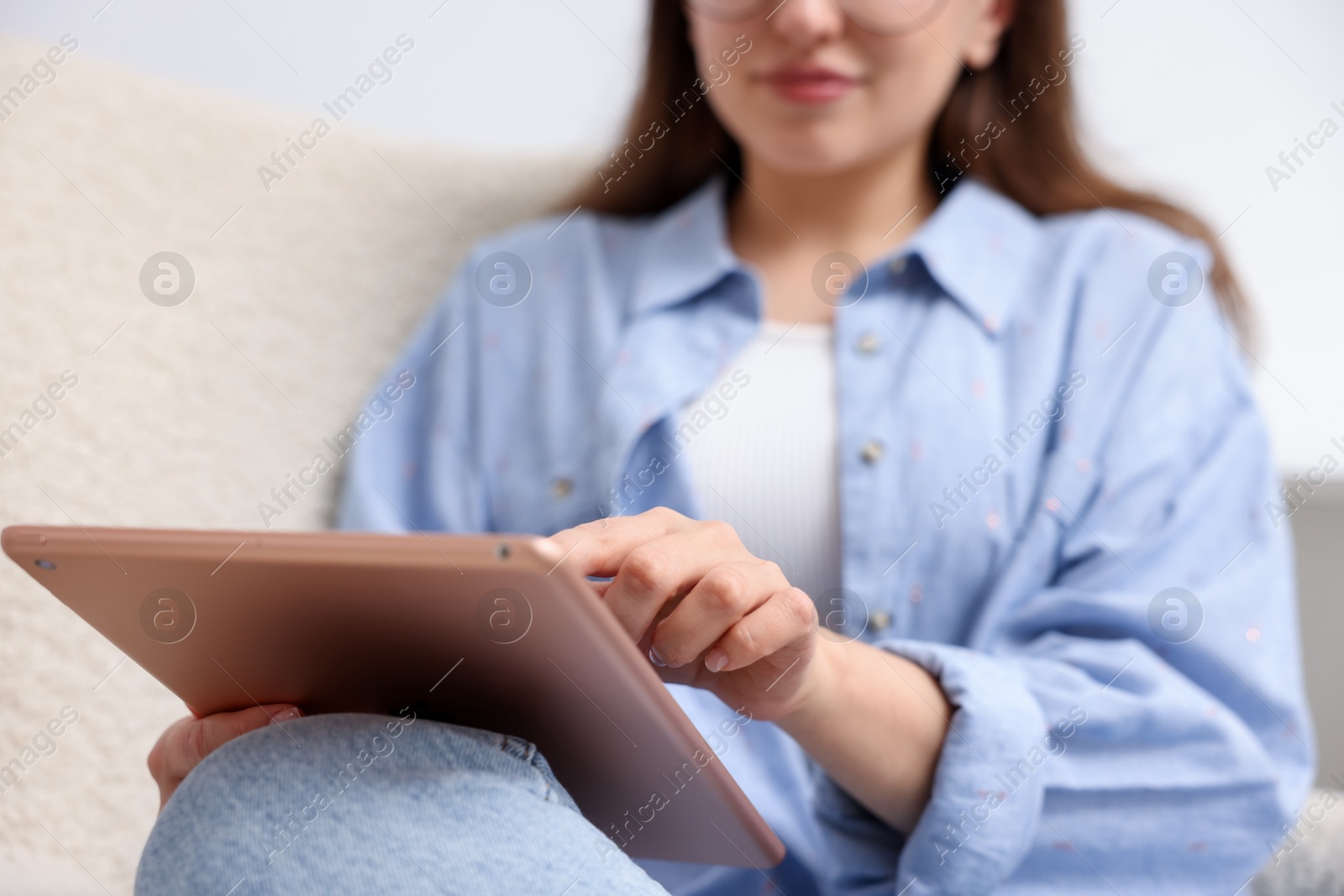 Woman using modern tablet in armchair at home, closeup Photo of Woman using modern tablet in armchair at home, closeup