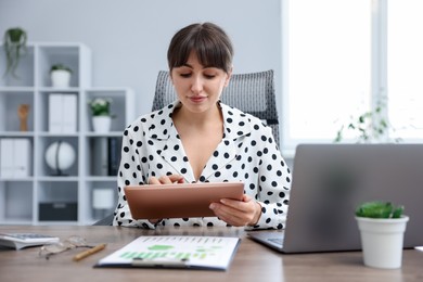 Photo of Woman using modern tablet at desk in office
