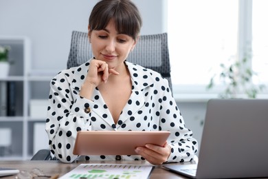 Photo of Woman using modern tablet at desk in office