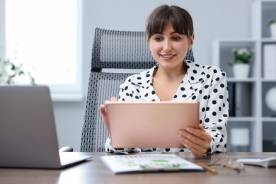 Photo of Woman using modern tablet at desk in office