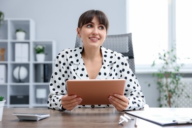 Photo of Woman using modern tablet at desk in office