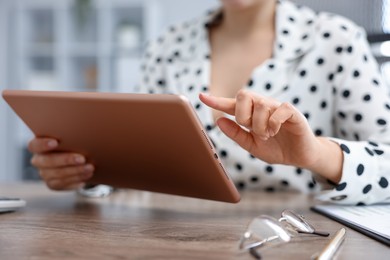 Photo of Woman using modern tablet at desk in office, closeup