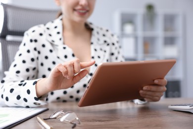 Photo of Woman using modern tablet at desk in office, closeup