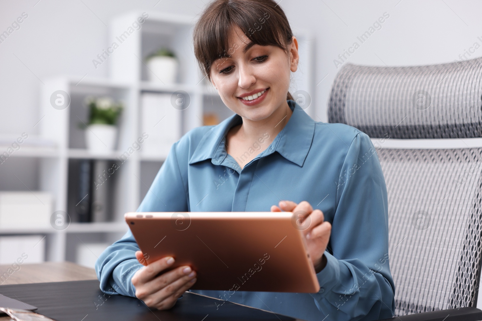 Woman using modern tablet at desk in office Photo of Woman using modern tablet at desk in office