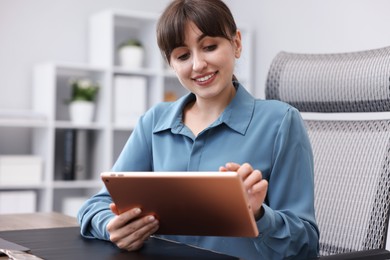 Photo of Woman using modern tablet at desk in office
