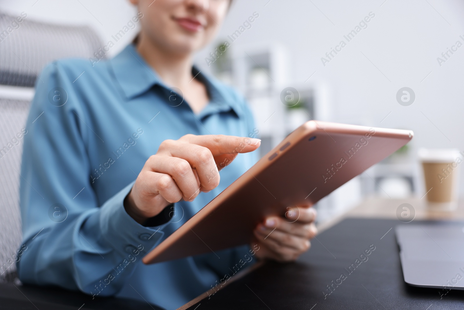 Woman using modern tablet at desk in office, closeup Photo of Woman using modern tablet at desk in office, closeup