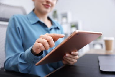 Photo of Woman using modern tablet at desk in office, closeup