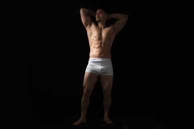 Photo of Young man in stylish white underwear on black background
