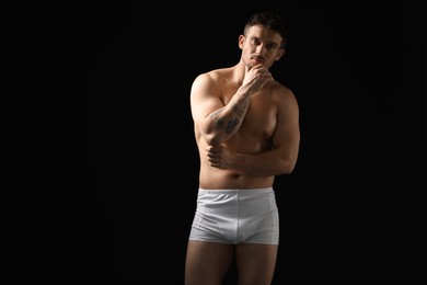 Photo of Young man in stylish white underwear on black background