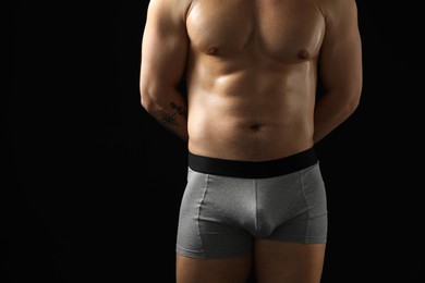 Photo of Young man in stylish light grey underwear on black background, closeup