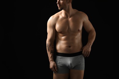 Photo of Young man in stylish light grey underwear on black background, closeup