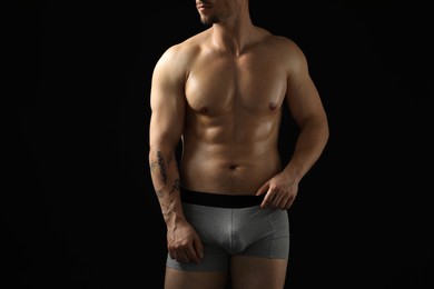 Photo of Young man in stylish light grey underwear on black background, closeup