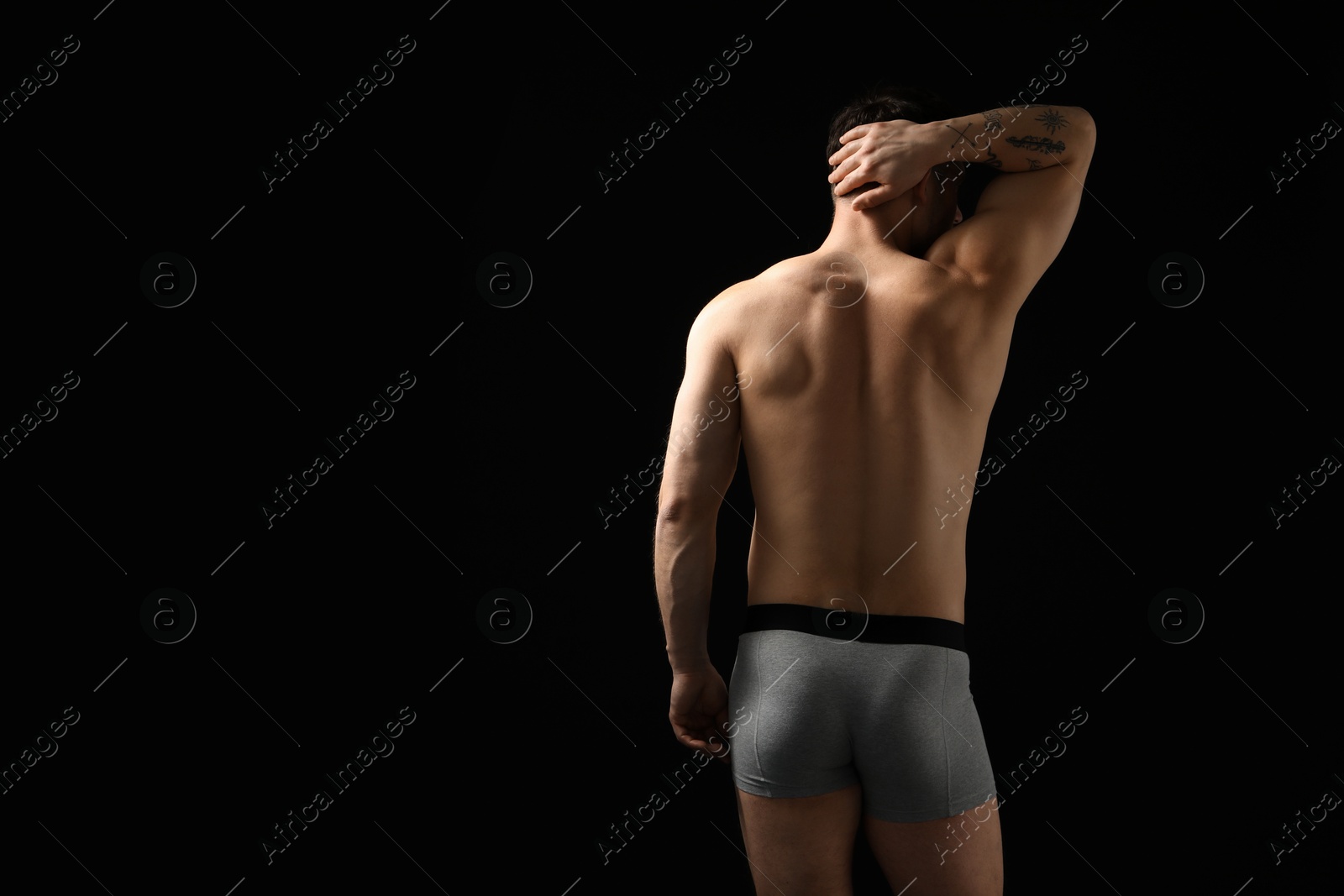 Young man in stylish light grey underwear on black background, back view. Space for text Photo of Young man in stylish light grey underwear on black background, back view. Space for text