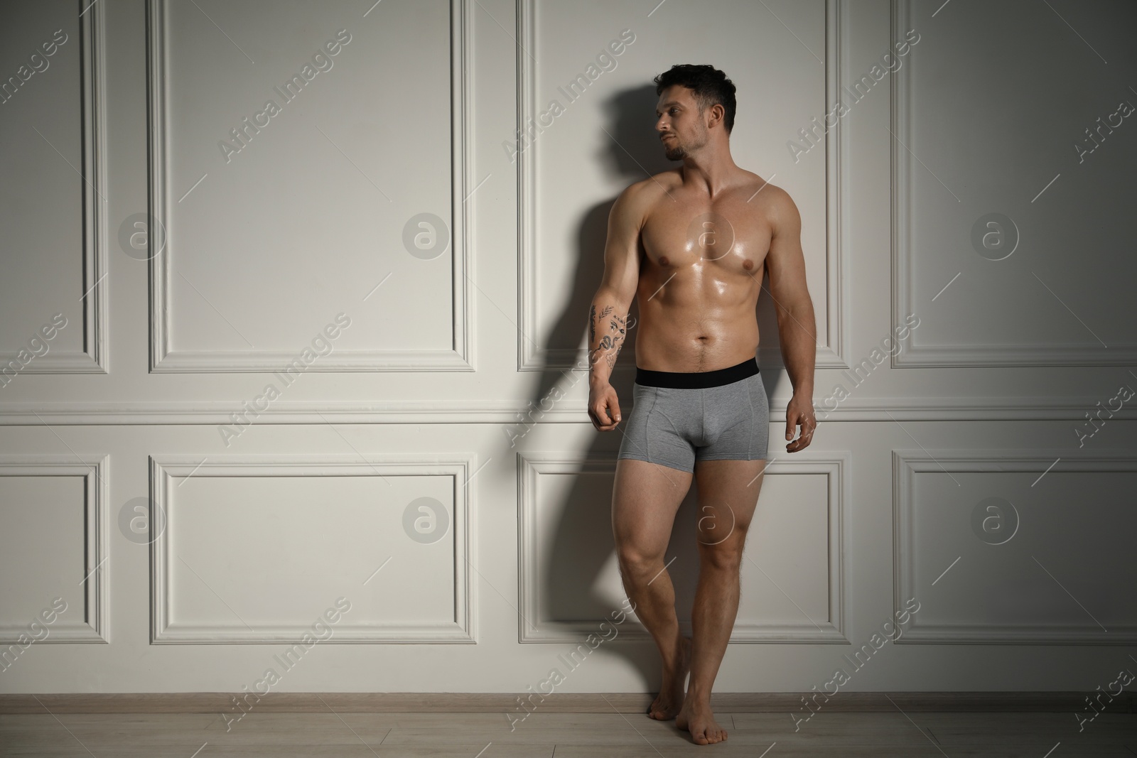 Young man in stylish light grey underwear near white wall indoors. Space for text Photo of Young man in stylish light grey underwear near white wall indoors. Space for text