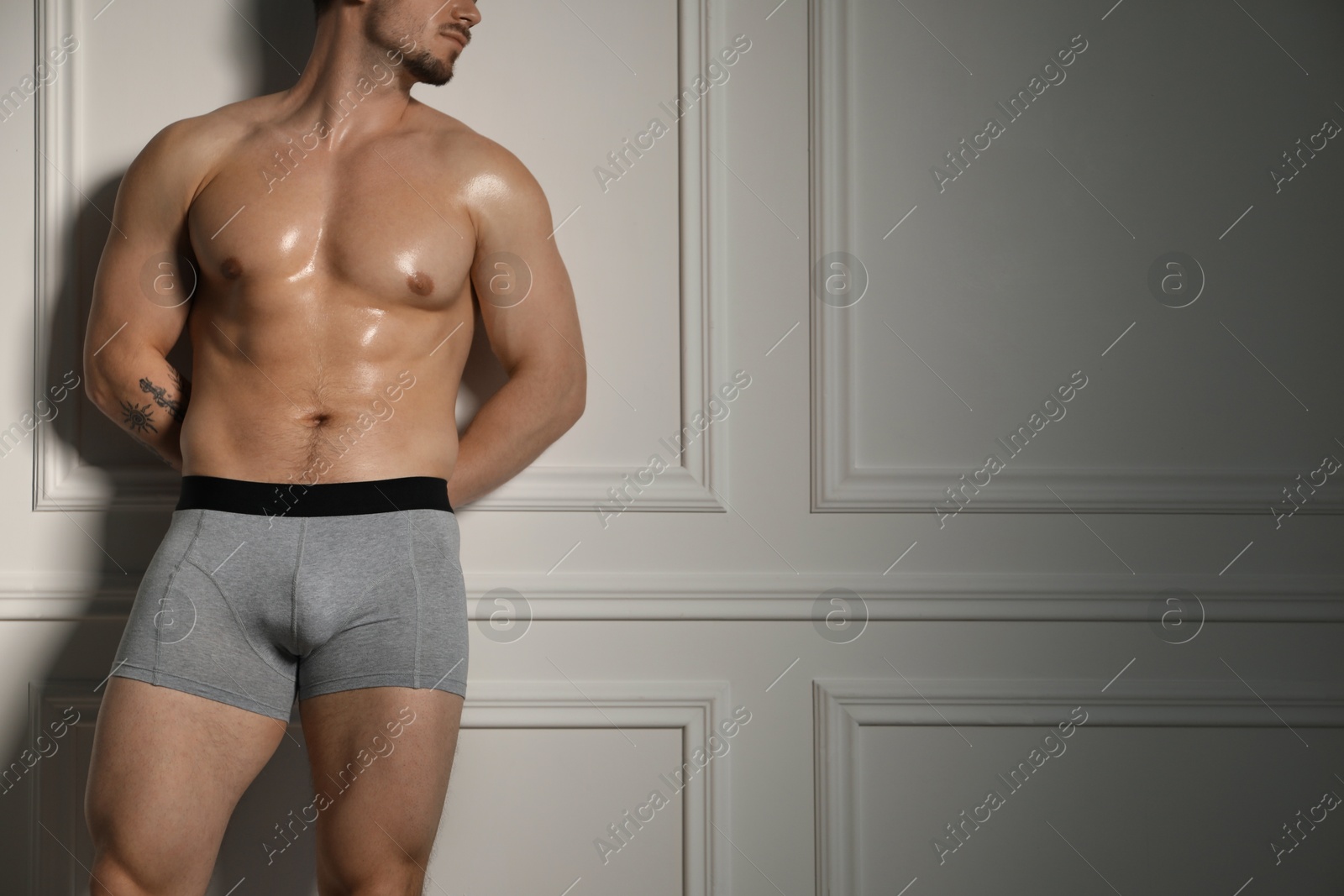 Young man in stylish light grey underwear near white wall indoors, closeup. Space for text Photo of Young man in stylish light grey underwear near white wall indoors, closeup. Space for text