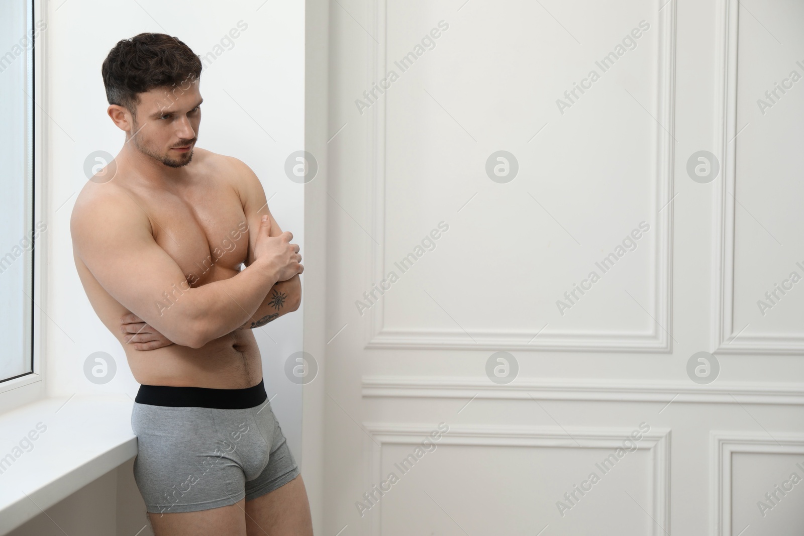 Young man in stylish light grey underwear near white wall indoors. Space for text Photo of Young man in stylish light grey underwear near white wall indoors. Space for text